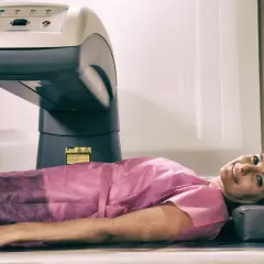 Kobieta leży pod aparatem do densytometrii, badanie wykrywa osteopenię.