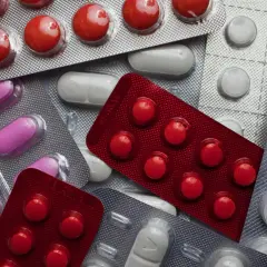 Opakowania leków, w tym czerwone tabletki, różowe kapsułki i białe tabletki. Możliwość zakupu Vermox bez recepty.