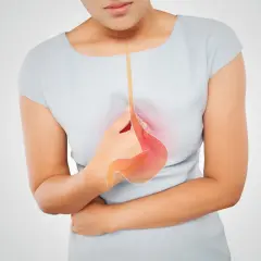 Kobieta w ciąży trzyma się za brzuch, odczuwając pieczenie. Grafika pokazuje przełyk i żołądek, symbolizując zgagę w ciąży.